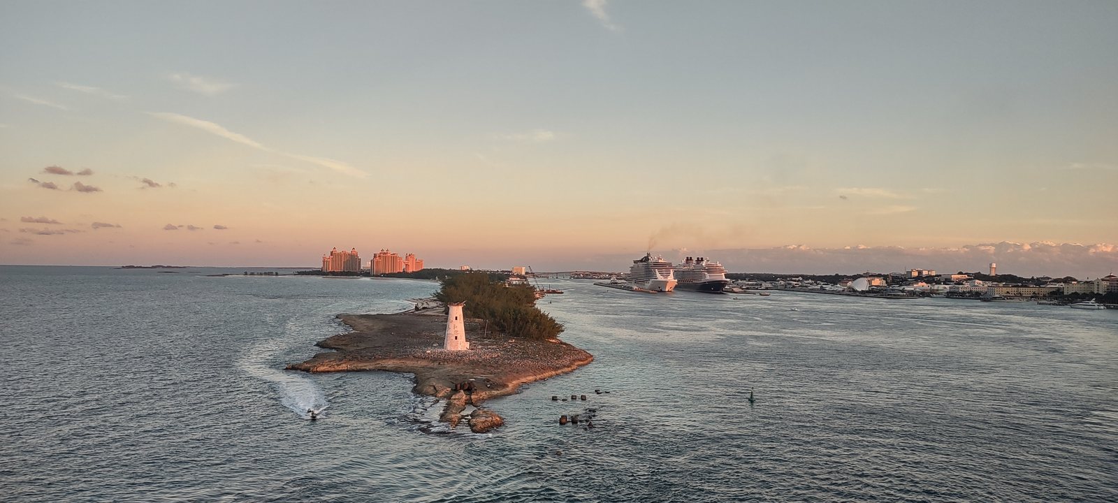 Nassau harbour at sunset, with the Paradise Island lighthouse in the foreground and a cruise ship sailing out
