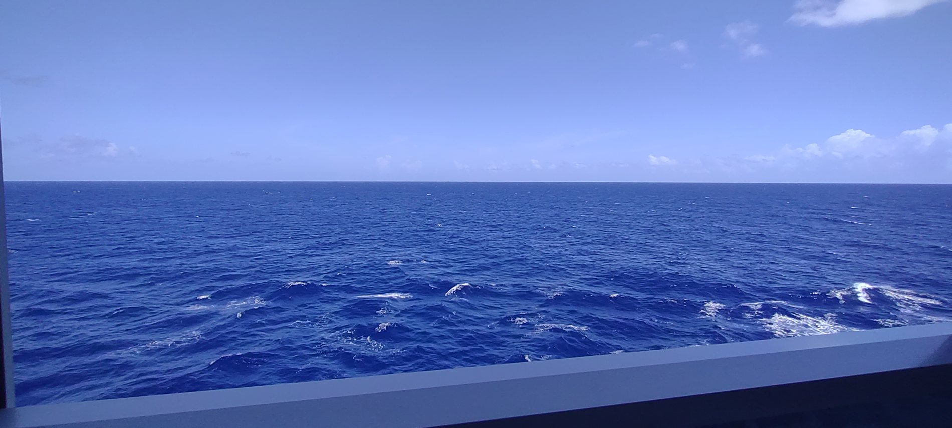 Wide open deep blue ocean seen from a cruise ship rail, nothing but water to the horizon